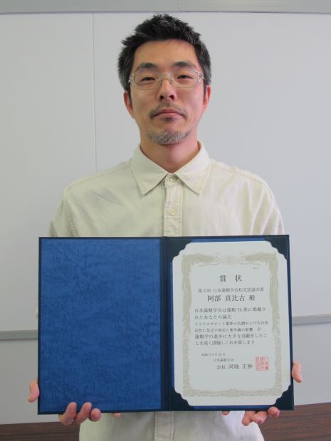 賞状を持つ生物生産学科 阿部真比古准教授の写真